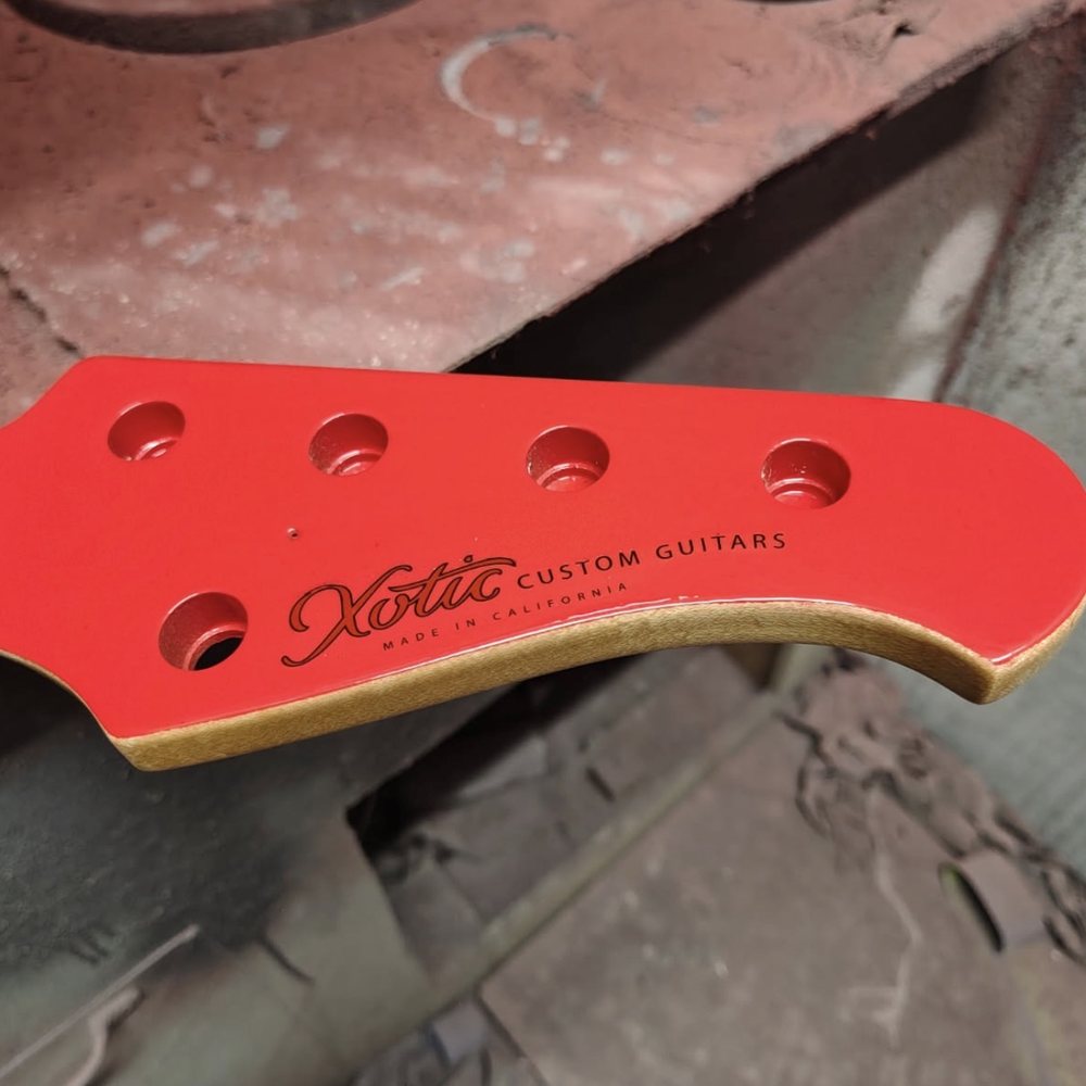Custom logo waterslide decal on a red bass guitar headstock