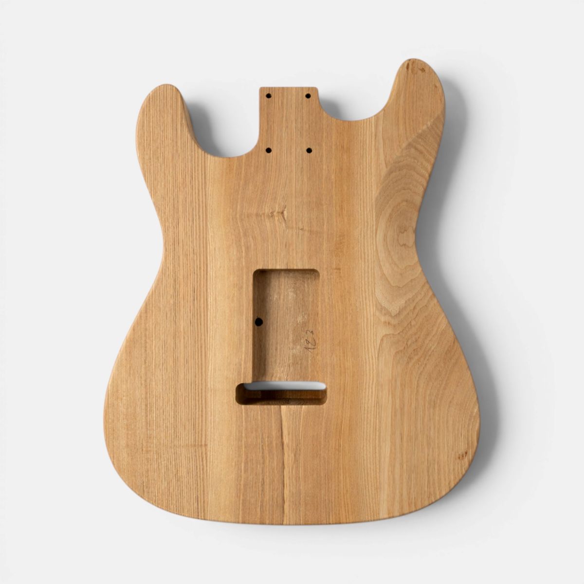 Backside of unfinished wood Strat guitar body shell with a double-cutaway shape, showing visible wood grain and pre-drilled screw holes